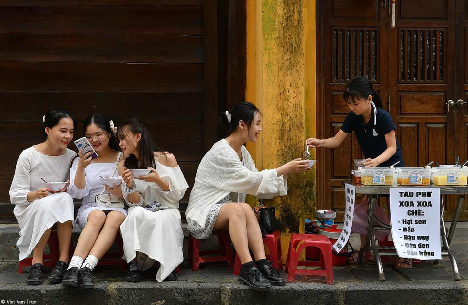 Girls eat che (sweet soup) on a street in Hoi An ancient town. Photo by Viet Van Tran.